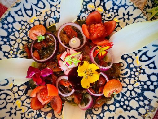 Appetiser with beautiful edible blooms garnish on gorgeous plate. 