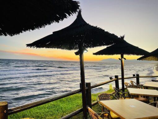 Tables set along beachfront with gorgeous sunset backdrop.