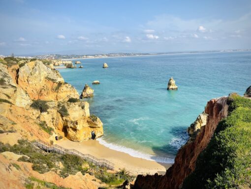 Breathtaking view of famous Praia do Camilo beach in Lagos with turquoise water against orange cliff and sandy beach.