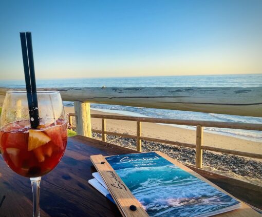 Glass of sangria on a table with view of the beach.