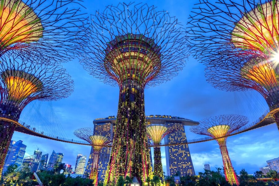 Super trees lit against background of iconic Marina Bay Sands building in Singapore.