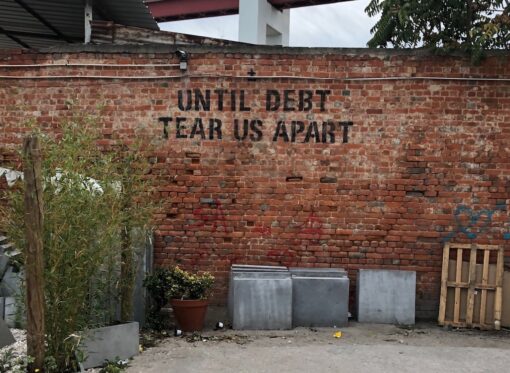 'Until debt tear us apart' graffiti on a brick wall.
