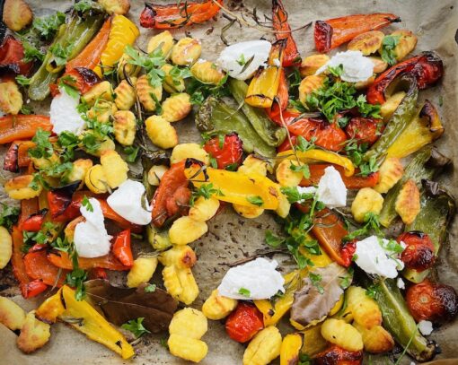 Tray of grilled colourful peppers, zucchinis, potatoes, herbs with sprinkling of mozzarella cheese. 