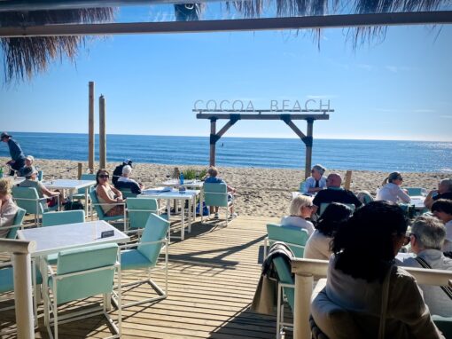 Beach restaurant on a bright sunny day, with view of ocean behind. 