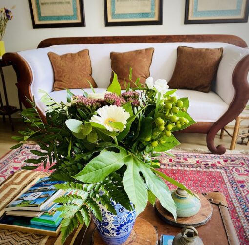 Cosy living room with antique sofa with floral arrangement foreground.