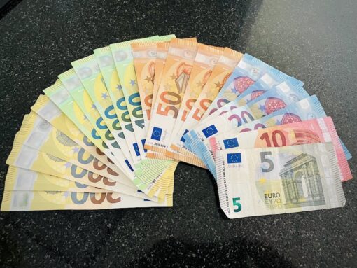 Euro notes of 200, 100, 50, 20, 10 and 5 denominations fanned out on a countertop.