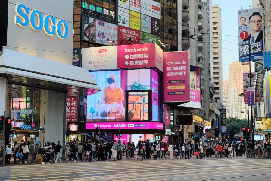 Busy street in Hong Kong teeming with pedestrians below gigantic advertising signboards.