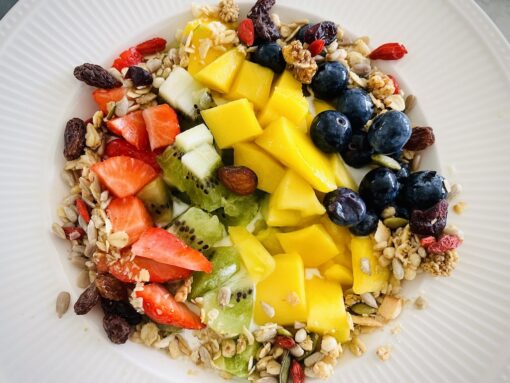 Delicious breakfast bowl of mango kiwi strawberries blueberries with granola and seeds. 