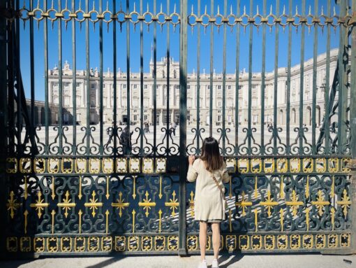 Woman peeping though the gates of the palace in Madrid.