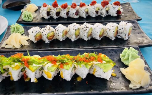 Platter of sushi rolls with garnishes of avocadoes, crab roes, wasabi and pickled ginger.