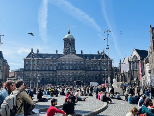 Famous Dam Square in Amsterdam where the Palace is located, buzzing with tourists on a sunny day. 