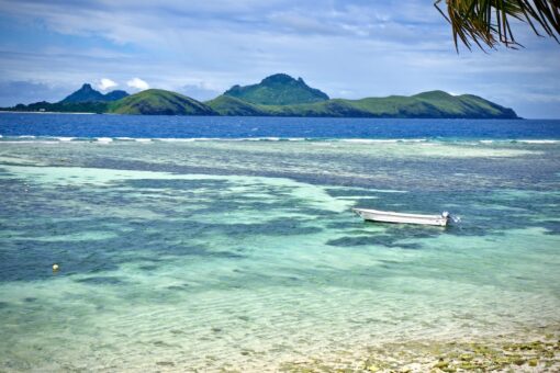 Boat sitting on crystal clear waters in the island of Tokoriki, Fiji.