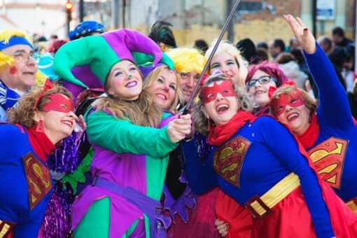 Middle-age folks at a carnival parade, several wearing Superman outfit.