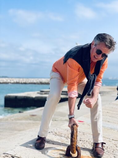 Man pulling at a chain bolted to the ground at a harbour.