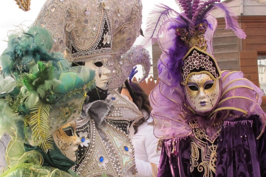 Carnival attendants in elaborate costumes and Venetian masks.