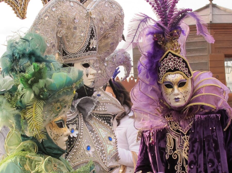 Carnival attendants in elaborate costumes and Venetian masks.