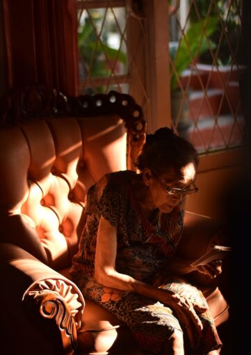 Elderly lady sitting forlornly alone at home in an armchair.