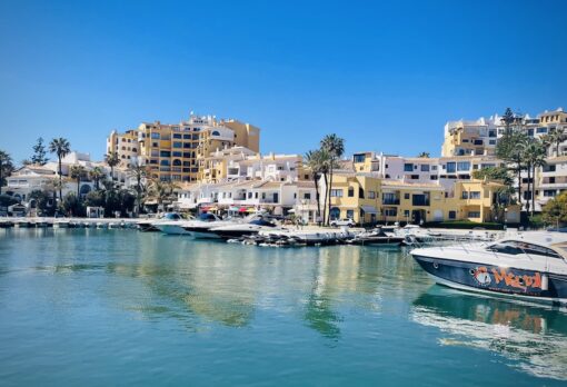 Marina with yachts and boards in front of high-rise apartments.