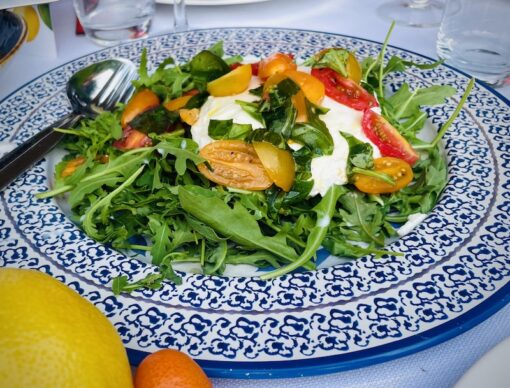 Salad of mozzarella with cherry tomatoes on a bed of rucola.