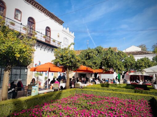 Plaza de los Naranjos square in Old Town Marbella with lunch crowd dining under sun shades surrounded by beautiful blooms.