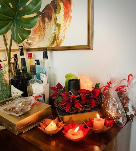 Side-table filled with Christmas gifts, candles and alcohol.