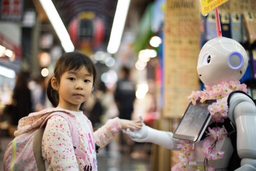 Young girl holding hand with a robot denoting human-robot connection.