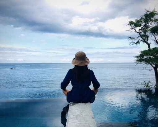 Shot of a women in meditation pose at edge of pool.