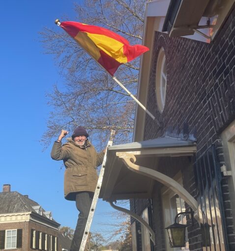 Elderly man pumping his fist after laying a flag into a flagpole.