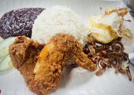 A favourite dish in Singapore - fragrant coconut rice with fried chicken wing, sunny side egg with peanuts and spicy sambal condiment.