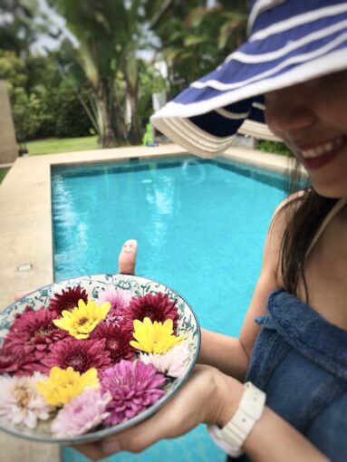 Smiling woman holding a plate of flowers at the pool.