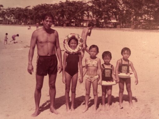 Young dad standing next to 4 children on the beach.