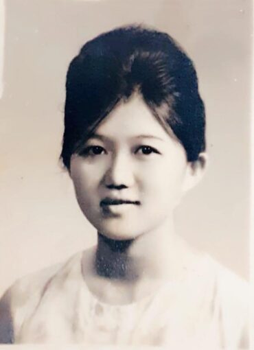 Black and white photo of a young Asian women with her hair burned up.