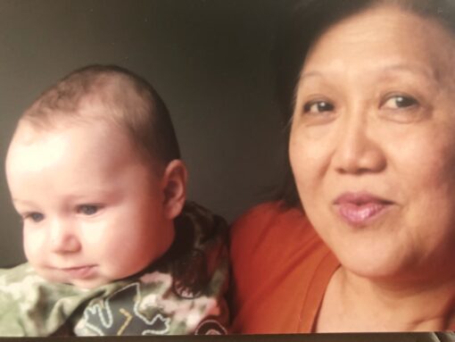 Asian woman holding a caucasian boy in arms.