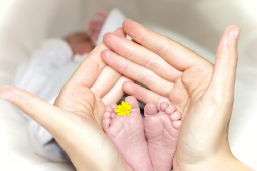 A pair of woman's hands holding baby's feet.