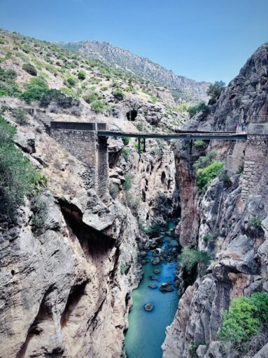 Breath-taking shot of river with a suspension bridge above it. 