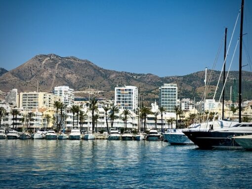 Apartments fronting a marina of turquoise water lined with yachts. 