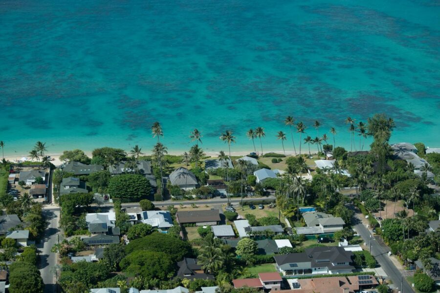 Drone shot from the air of beach-front properties along crystal clear water.