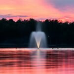 Sprouting fountain in the middle of a lake in soft pink sunset light.