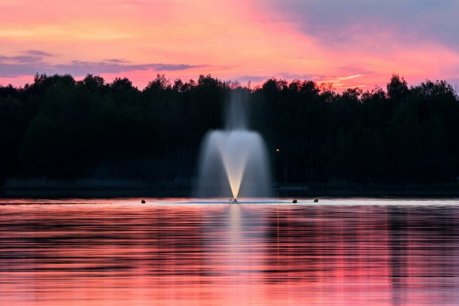 Sprouting fountain in the middle of a lake in soft pink sunset light.