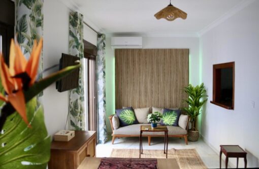 Photo of a small modern tropical living room with tasteful accent of wood panels and cosy sofa wit lots of cushions.