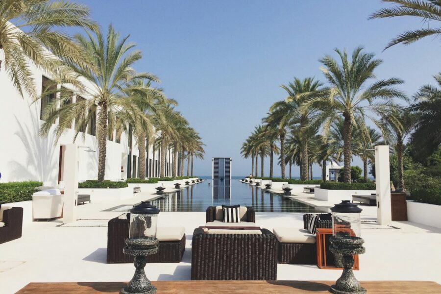 View of infinity pool with palm trees long both sides and lounge chairs.