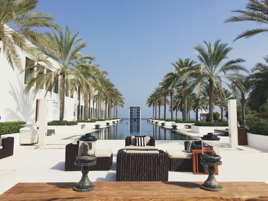 View of infinity pool with palm trees long both sides and lounge chairs.