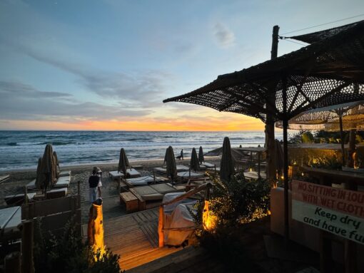 Beach front restaurant with colourful sunset in background. 