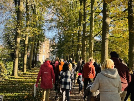 Group of people walking along a forested path in winter clothes on a sunny day. 