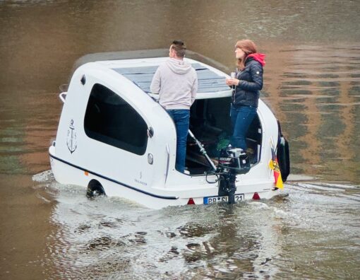 A car converted to a boat riding down a canal. 